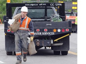 City of Calgary worker Jim Hawkins carries sandbags as city workers start to build a berm along Elbow Drive at 25th Street S.W. on Thursday as the Elbow River began to rise following heavy rains. A mandatory evacuation alert was issued for the communities around the Elbow River.