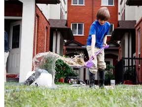 Daniel Boddy, nine, helps with cleanup work as hoses drain water from flooded basements in Bridgeland June 23, 2013.