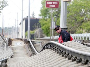 Dean Hagen of the Calgary Transit Track and Way Department surveys the mess of rail lifted and twisted off it’s bed north of the Stampede Erlton C-Train Station Sunday June 23, 2013. Adjacent Macleod Trail northbound lanes were also destroyed. (Ted Rhodes/Calgary Herald) For City story. Trax # 00046339A