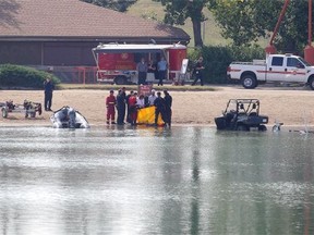 Divers remove what is believed to be the remains of a suspected drowning victim from Sikome Lake in Fish Creek Provincial Park in Calgary on Wednesday.