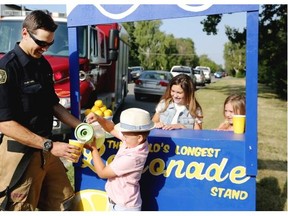 Easton Krivak, 5, serves some lemonade to firefighter Tyler Rabel. Dare to Care will attempt a Guinness World Record on Sept. 18 for the world’s longest lemonade stand.