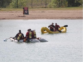 Emergency service personnel search for the body of a suspected drowning victim at Sikome Lake in Calgary on Tuesday.