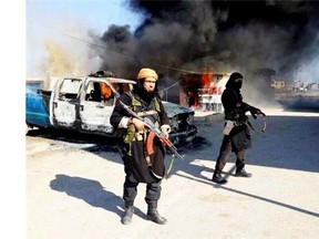 Fighters with the Islamic State of Iraq and the Levant in Iraq stand next to a burning vehicle in Iraq’s Anbar Province. The terror group aims to establish a Shariah-ruled mini-state bridging Iraq and Syria.