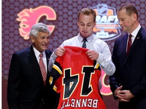 Flames first-round pick Sam Bennett pulls on a jersey while flanked by Tom Webster and GM Brad Treliving.