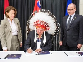 Former premier Alison Redford and Transportation Minister Ric McIver looked on as Tsuu T’ina Chief Roy Witney signed the southwest ring road deal at the Sarcee Seven Chiefs Sportsplex in November 2013.