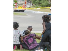 Friends and family console a woman who watches emergency crews clean up around her home which she has just lost to fire on the 14,000 block of Mt. McKenzie Dr. SE in Calgary, on August 6, 2014.