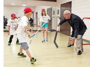 Grade 5 students, from left, Jaswanth Gangavarau, Kaelan Purdie and Ella Batzel watch as a ball sails past Calgary Flames president and CEO Ken King on Thursday after the announcement of the Flames Foundation partnership for a program with the YMCA to provide all Grade 6 students in Calgary with a free membership beginning Sept. 1.