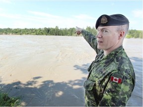 Maj. Graham Longhurst with the 41 Canadian Brigade Group explains where support wires have been swept away and the river bank eroded away as members of the Canadian Military moved in to help protect Enmax’s substation 32 in Douglasdale on Sunday.