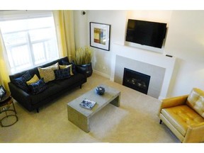 The great room of the Birchfield show home features a large window and a central fireplace with a mantel to protect a television from heat.