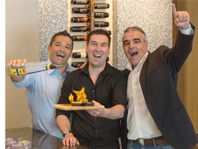 GreekTown owners, Harry Diamantopoulos, left, and Costa Floras, right, with a member of their wait staff, Harry Giannakopoulos, centre, show off some flaming cheese saganaki.