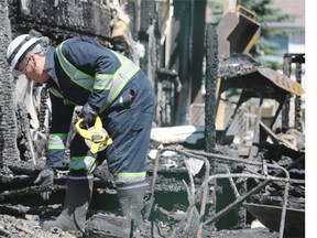 An insurance investigator sifts through charred debris as two houses on Castlebrook Rd. N.E. were severely damaged in an overnight fire. 
 ({David Moll}/Calgary Herald)