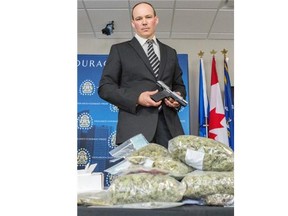 Jenn Pierce, Calgary Herald 
 Calgary, AB; APRIL 8, 2014  -- Sgt Jason Walker, with the guns and gangs unit, displays the drugs and weapons seized after a reported home invasion in Calgary on Thursday May 8, 2014. Seven people have been charged with numerous drug and weapons charges. (Jenn Pierce/Calgary Herald) For City story by Clara Ho. Trax # 00055283A