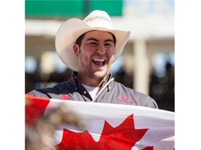 Morgan Grant of Granton, Ont., celebrates after taking home the bronze trophy in the Tie Down Roping event on Sunday at the Calgary Stampede.