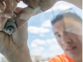 Josh Wong repairs vehicle windshields’ cracks and chips for Deco Windshield Repair at the Sunridge Mall parking lot.