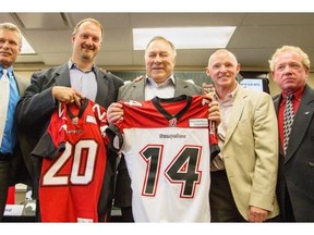 Stu Laird, from left, Jamie Crysdale, Ron Allbright, Pat Clayton and George Hopkins receive jerseys at a press conference announcing them as the  Stampeders’ 2014 Wall of Fame class on Monday. Inductee James Sykes wasn’t present for the media availability.