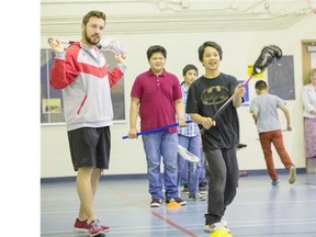 Dan MacRae, left, of the Calgary Roughnecks takes part in some lacrosse drills with a group of Grade 6 students from St. Bernadette school in Calgary on Wednesday.
