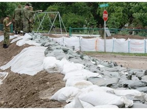 Members of the Canadian Forces on Monday look over a dike they constructed in Medicine Hat.