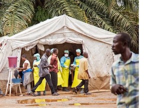 Canada is bringing three scientists home from Kailahun, Sierra Leone, a post which the World Health Organization has temporarily closed to investigate the infection of an international medical responder working there. In this photo taken Saturday, Aug. 9, 2014, health workers, center rear, screen people for the Ebola virus before entering the Kenema Government Hospital in Kenema, 300 kilometers, (186 miles) from the capital city of Freetown, Sierra Leone.