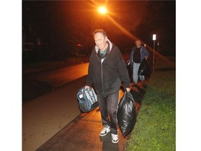 Mission residents Wayne Nordli and Doug Allard pack up their kits and trudge along 24th Avenue after a forced evacuation of the neighbourhood Thursday night. By early Friday, displaced residents hoping to find a hotel room in Calgary had very few options.