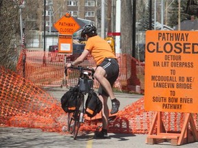 A cyclist vaults the netting marking a closed section of the Bow River Pathway along Memorial Drive between the Bridgeland LRT and the new St Patrick's Island Bridge Monday May 12, 2014. Numerous sections of city pathways are closed.