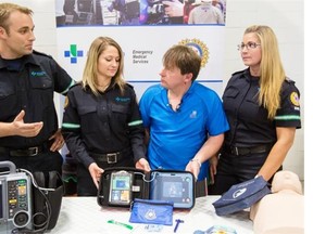 David Horan, in blue, reunites Tuesday with the EMS team that saved his life in April 2013: paramedic Greg Sikora, from left, EMT Sarah Van Den Brink and paramedic Kerri-Ann Andrais. Horan raised funds to help buy a defibrillator to give back to the organization.