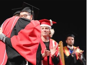 Miles Hong, right, accepts his brother Lawrence Hong’s posthumous degree during graduating ceremonies at the University of Calgary.
