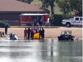 Divers remove what is believed to be the remains of a drowning victim from Lake Sikome in Fish Creek Provincial Park in Calgary, Alberta Wednesday, August 13, 2014. A 29 year-old man is missing after an incident on the water Monday.