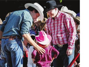 Prime Minister Stephen Harper, right, greets Liberal Leader Justin Trudeau and his children while attending the Calgary Stampede parade on Friday.