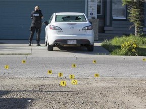 Multiple evidence markers are visible on the street at the scene of a shooting at Anaheim Circle N.E.
