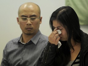 Marco Luciano looks on while  Junniflor Magno sheds a tear during a press conference to respond to a recent moratorium in the Temporary Foreign Workers program in Edmonton on Monday May 5, 2014