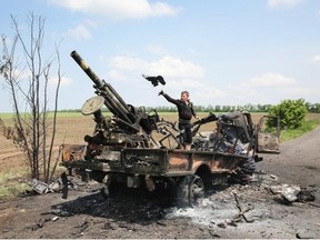 Residents scavenge parts from a burned Ukrainian military vehicle on Wednesday in Dmytrivka, near Kramatorsk. Alberta is boycotting a petroleum summit in Russia over its meddling in Ukraine’s affairs.