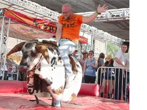 Patrick Cote rides the mechanical bull at Stampede Park in Calgary on Friday.