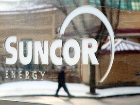 A pedestrian is reflected in a Suncor Energy sign. The company has plans to expand production through several debottlenecking projects.