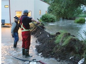 People work to build a berm to protect the Tenove family’s home on the outskirts of Nanton as Mosquito Creek flooded late Thursday.