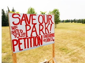 A petition sign stands in a park that is slated for a francophone school in Scenic Acres on July 15. Despite local opposition to the school, the chair of Calgary’s francophone school says it won’t deter construction from starting as early as next year.