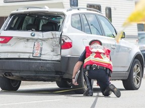 A police officer surveys the scene where a motorcycle slammed into the back of an SUV on Macleod Trail at Mission Road on Friday.