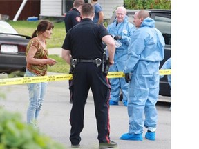 Police talk with a neighbour at the scene of a suspicious death on Saturday afternoon July 26, 2014