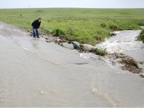 Rick Tailfeathers, Blood tribe communications officer, stands near a washed out road on the Blood reserve after flooding in the area.