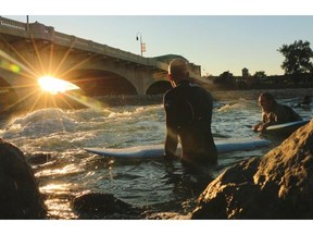 River surfers surf the wave close to the 10th Street bridge on the Bow River.