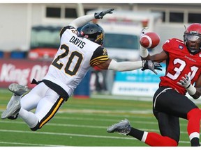 Calgary Stampeders receiver Jeff Fuller could not quite hold on to this pass as Ti-Cats defensive back Emanuel Davis jumps to block in the first quarter of their CFL game at McMahon Stadium in Calgary on Friday evening July 18, 2014.