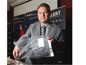Staff Sgt. Martin Schiavetta holds a weapon seized after three arrests were made affiliated with the Red Scorpions gang.