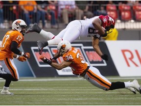 Stampeders receiver Nik Lewis, top, is upended by B.C. Lions defender Torri Williams (34) as T.J. Lee, left, moves in for the tackle during the first half of the Lions 37-13 win over Calgary Friday night at BC Place Stadium.