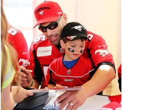 Stamps’ Randy Chevrier had some help from his son Kyle, 2, while signing autographs as the Calgary Stampeders hosted annual Fanfest event on May 24.