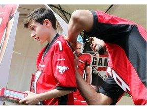 Stamps star running back Jon Cornish signs Zachary Gail-Ryan’s touchdown kid jersey, and his box of Cornish Flakes, as the Calgary Stampeders hosted their annual Fanfest  event on Saturday.