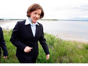 Then-premier Alison Redford walks near the Gleniffer reservoir, with an oil-containing boom across it, after a Plains Midstream pipeline leak fouled the water in June 2012. The company has passed an audit of its operations.