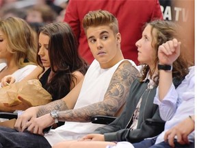 This May 11, 2014 file photo shows singer Justin Bieber, center, watching the Los Angeles Clippers play the Oklahoma City Thunder with his mother Pattie Mallette, second from left, in the first half of Game 4 of the Western Conference semifinal NBA basketball playoff series in Los Angeles. Los Angeles police said Wednesday May 14, 2014, that they have opened an attempted robbery investigation involving Bieber after receiving a report that the pop singer tried to take property from a person at a Los Angeles family entertainment center on Monday night. (AP Photo/Mark J. Terrill, FIle )