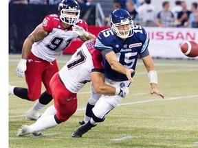 Toronto Argonauts quarterback Ricky Ray manages to avoid being sacked by shoveling a pass forward as he is tackled by Calgary Stampeders’ Jeff Hecht during fourth quarter action in their CFL game in Toronto on Saturday.