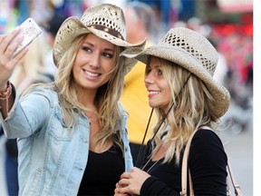 Vancouverites Kristen Jensen, left, and Laila Potvin mugged for their camera as they snapped a photo of themselves decked out in western wear while visiting the midway during the 2013 Stampede. Technically, photos such as these are not supposed to be shown on social media, but the Stampede says those rules will be revisited and attendees are welcome to post Stampede pictures.