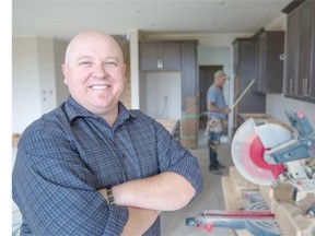 Wayne Copeland, president of the Canadian Home Builders Association-Calgary Region, in an under-construction home, as finishing carpenter Chris Barrett, of Country Sky Carpentry Inc., continues working around him in Calgary.