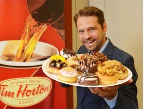 Actor Jason Priestley holds a plate of donuts in Oakville, Ont. on July 30, 2013 as part of a Tim Hortons promotion and contest.